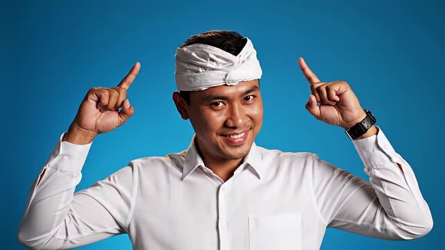 Young Asian man in traditional Balinese udeng points to his head, symbolizing a new idea or creative solution. Represents innovative thinking, inspiration, problem-solving, and smart strategy for...