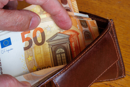 Hand taking a 50 Euro banknote from wallet, cost of living, wages, or inflation concept.