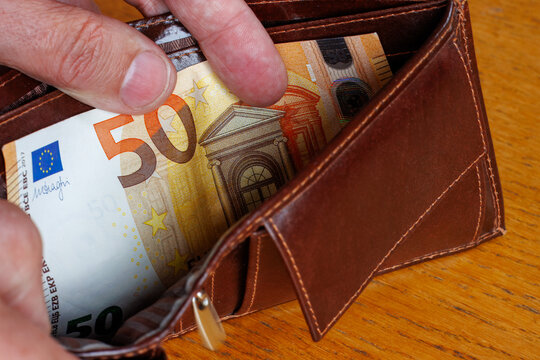 Hand taking a 50 Euro banknote from wallet, cost of living, wages, or inflation concept.