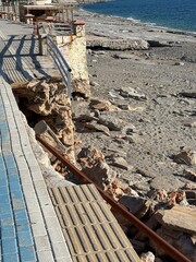 Rocky coastal erosion on a sunlit day with stone walls and water in the background © dvoevnore