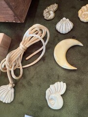 Carved shell ornaments and rope displayed on textured olive green background © dvoevnore