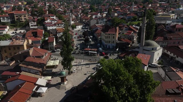 Cinematic Drone Pull Back of Sebilj Fountain in Bascarsija Square, Aerial View of Historic Wooden Landmark and Pedestrians in Old Town Sarajevo Bosnia, 4K