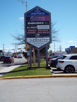 Gatineau, Quebec, Canada &ndash; May 10, 2026: A tall, "multi-tenant monument sign" displays various professional business listings along a busy road on Bd de l'H&ocirc;pital.
