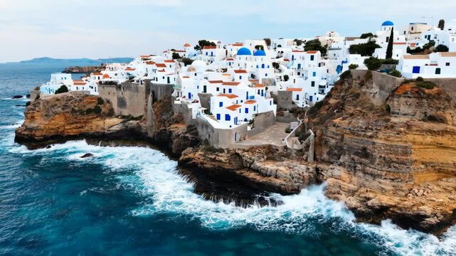 Beautiful white houses with blue domes on a rocky cliff overlooking the blue ocean in greece