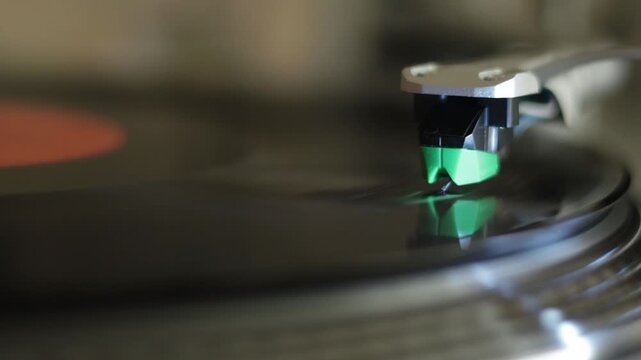 Cinematic close-up video of a turntable cartridge tracking a spinning vinyl record. Shallow depth of field and smooth motion create a nostalgic analog music atmosphere with a warm aesthetic mood.