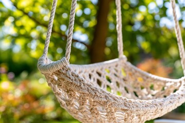 Obraz premium Empty macrame hammock chair hanging in a sunny garden oasis