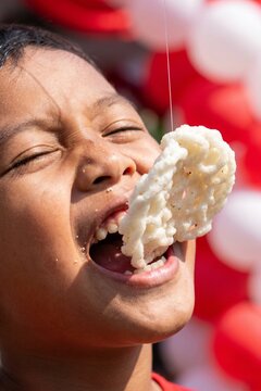 Boy Eating Cracker Hanging on String Indonesian Independence Day Celebration