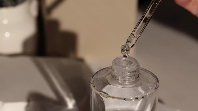 A person uses a dropper to release liquid from a bottle. The process shows each step clearly. This action focuses on precision and control.