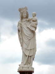 Obraz premium Statue de la Vierge à l'Enfant sur fond de ciel nuageux