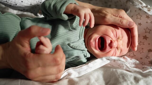 Distressed newborn baby crying loudly while a mother's gentle hands try to soothe and comfort the infant, a poignant close up moment highlighting the challenges and emotions of early parenthood