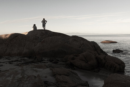  desaturated image of 2 boys sitting on boulder overlooking Saldanah Bay, Western Cape, South Africa