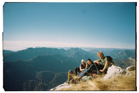 Friends Enjoy a Mountain View at a Summit in the Daytime