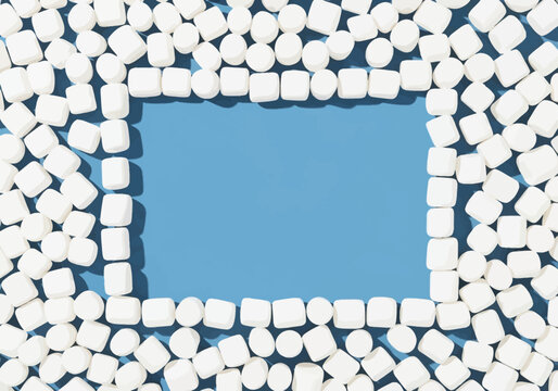Top-down view of soft white marshmallows forming a rectangular frame on a solid blue background, with extra marshmallows filling the outer edges and a clear central copy space area.