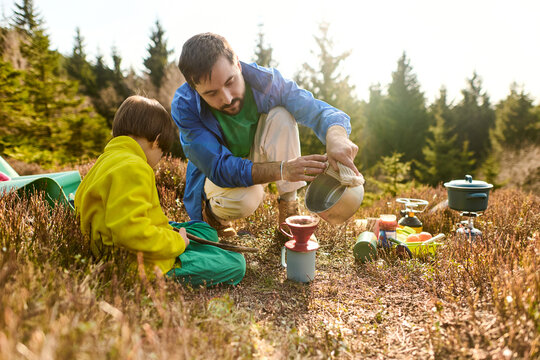 Father and son making coffee while camping