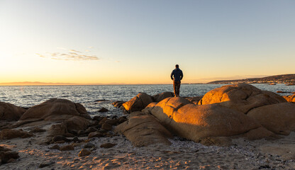 silhouette of man viewing sunrise atop boulder rock, Saldanah Bay, Western Cape, South Africa © Marc Romanelli