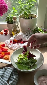 Person preparing fresh summer salad in sunny kitchen