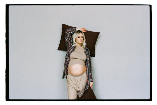Pregnant woman with pillows against the wall.