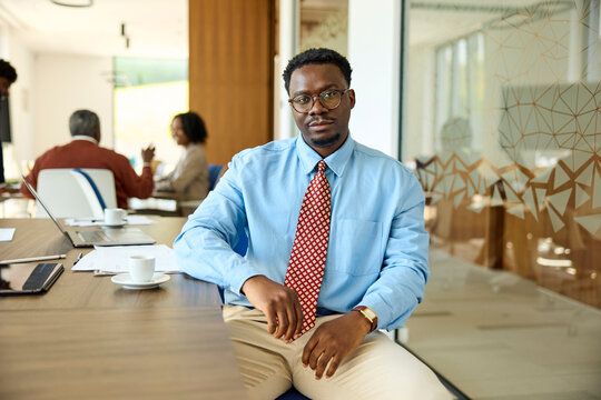 Relaxed businessman seated at his desk, looking at the camera