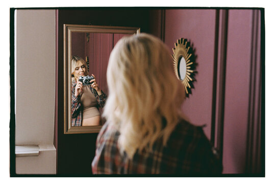 A pregnant woman takes a picture of herself in a mirror