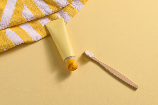 Yellow toothpaste tube and bamboo toothbrush with paste on yellow