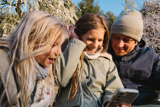 Father with daughters looking at the screen of the phone outdoors