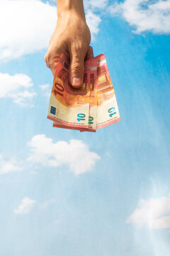 Hand holding euro banknotes against blue sky