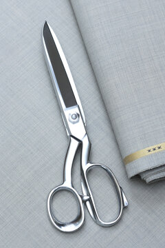 Premium light gray Super 180s wool suiting fabric featuring an elegant sharkskin weave, classic pick-and-pick texture, and a sophisticated micro-check pattern with scissors atop for luxury tailoring.