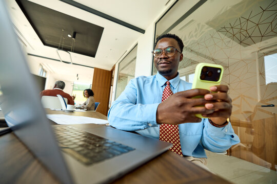 Man sits at the office, using his laptop and a phone