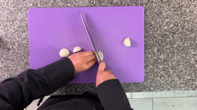 Professional chef finely mincing garlic cloves