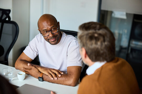 Two men discuss work indoors