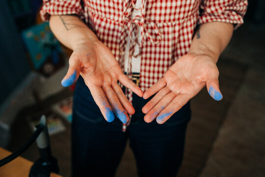 Artist showing hands covered in blue paint after creative work