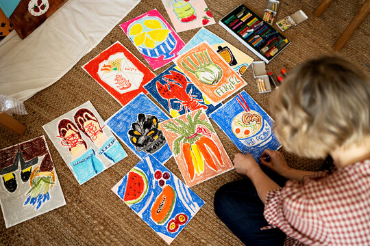 Artist sitting on floor creating colorful food illustrations wit