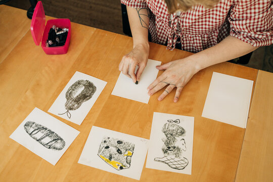 Artist drawing black and white sketches on paper at wooden desk