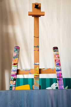 Wooden easel with colorful paint marks in artist studio