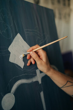 Artist hand painting white shape over sketched composition
