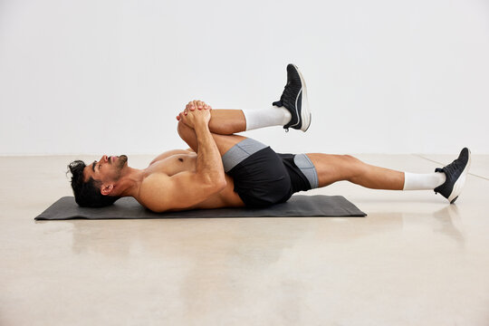 Man stretching on mat in gym during exercise routine
