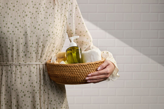 Woman holding a woven basket filled with bathroom essentials