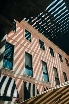 Sunlight stripes across pastel building facade in urban setting