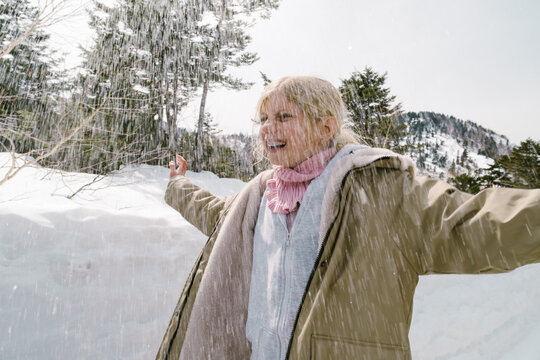 Happy girl under the falling snow outdoors