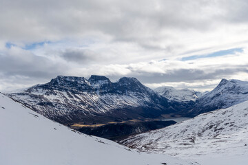 Obraz premium A beautiful winter landscape with snowy mountains in an overcast day. A wintertime scenery near Eidsdal in Geiranger Unesco World Heritage site, More og Romsdale region, Norway.