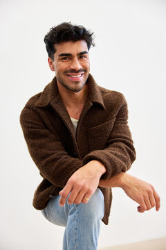 Man smiling while sitting on the floor and posing for a casual p