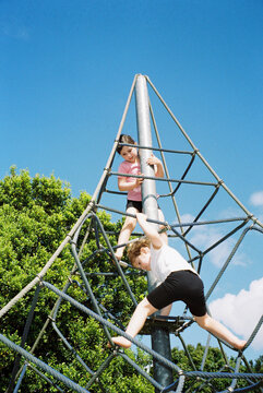 Two young girl playing on climbing frame at an Australian park.