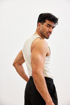 Muscular man posing in a simple, bright indoor space during dayt