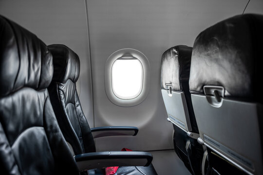 Airplane cabin interior, empty comfortable passenger seats in economy class with portholes.