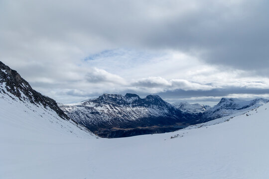 A beautiful minimalist landscape of snowy mountain peaks and clouds in the sky. A wintertime scenery near Eidsdal in Geiranger Unesco World Heritage site, More og Romsdale region, Norway.