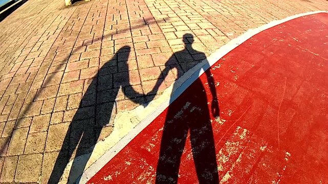 the shadow of a boy and a girl holding hands