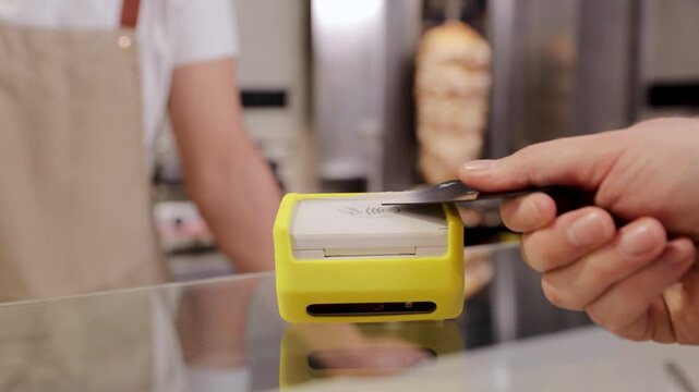 Customer making a fast, secure, and modern contactless payment transaction using a credit card on a portable nfc terminal