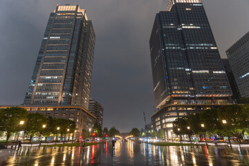 Obraz premium 雨の東京駅前にそびえる丸ビルの夜景 Rainy Night View of Marunouchi Building Near Tokyo Station, Japan