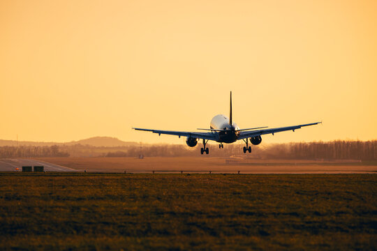 Silhouette of commercial airplane landing on airport runway during at dusk. Aviation transport, international travel, airline cargo and tourism concept with copy space.