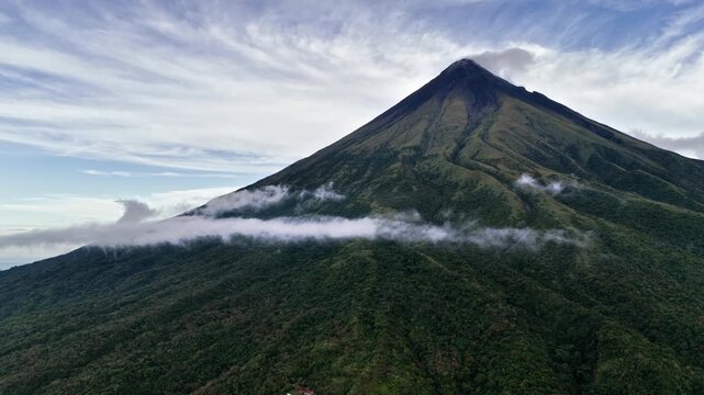 Horizontal panning aerial shot of Mayon Skyline Park revealing the perfectly shaped Mayon Volcano. Low altitude thin clouds drift along the mountain slope, Philippines